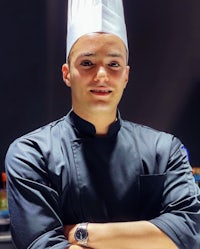 a chef wearing a chef's hat is posing for a photo