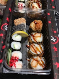 a variety of sushi in plastic containers on a table