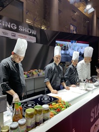 a group of chefs preparing food at a cooking show