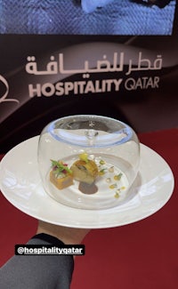 a person holding a plate with the words hospitality qatar on it