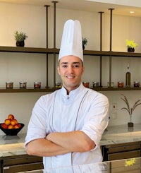 a chef standing in front of a counter with his arms crossed