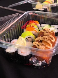 a variety of sushi in plastic containers on a table