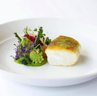 a white plate with a fish and vegetables on it